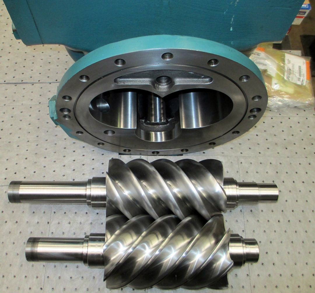 Rotores macho y hembra de compresor de tornillo junto a la carcasa abierta